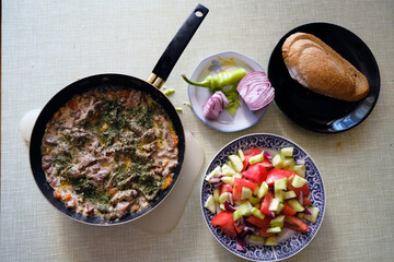 Fresh mushroom saute with bacon and vegetables, decorated with salad on a kitchen table, top view 