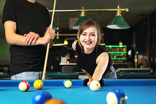 Pool game. A woman and a man are playing pool in the club
