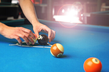 Playing billiards, the player sets the balls on the pool table. © Robert Przybysz