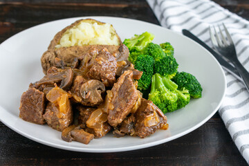 Steak Diane Casserole with Sides: Chunks of beef, onion, and mushrooms in a tomato sauce served with broccoli florets and a baked potato