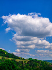 Clods in an almost perfect row in the blue sky over hilly landscape