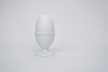 White egg on a white background, with a cup