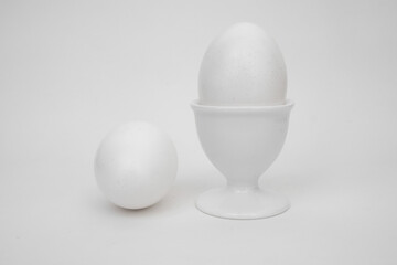 White eggs on a white background, with a cup