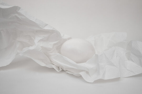 White eggs on a crushed white napkin, white background
