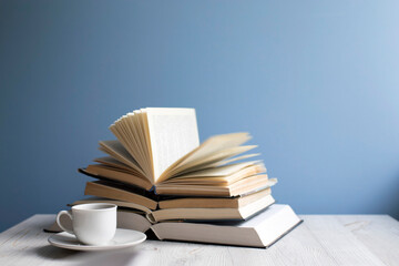 open book and cup of coffee on a background of a blue wall. Concept - online learning.
