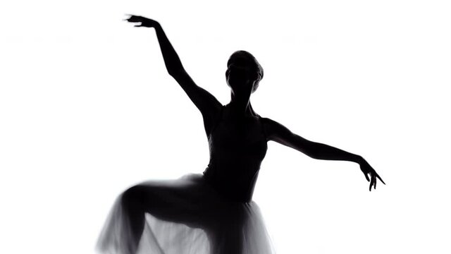 Silhouette of ballerina performing classical dance moves against white background