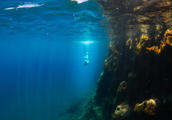 Fototapeta na wymiar Beautiful girl swimming and freediving in the blue crystal clear mediterranean sea