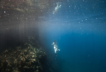 Fototapeta na wymiar Beautiful girl swimming and freediving in the blue crystal clear mediterranean sea