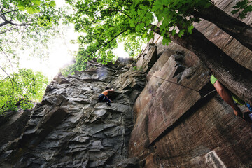 Climber extreme girl climbs a rock on a top rope. Summer of 2020, Buky canyon in Ukraine
