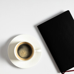 White office desk. Notebook, black headphones and coffee cup on white background.  Flat lay, top view, copy space