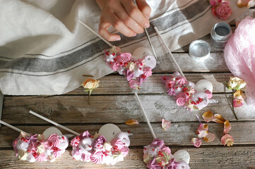 Hands paint a brush marshmallow in the form of a pony on sticks. Work at home. Horizontal photo.