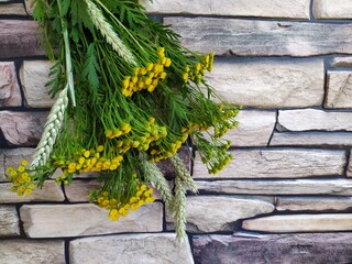 Bouquet of yellow field flowers tansy on the brick stone background