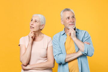 Pensive elderly gray-haired couple woman man in casual clothes posing isolated on yellow background...