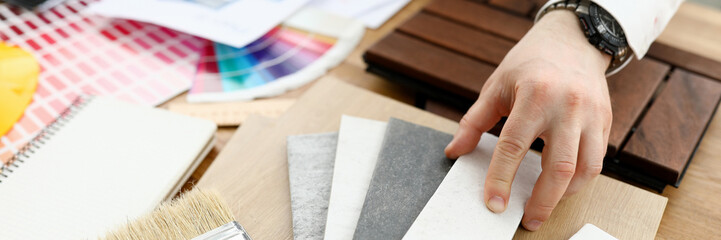 Male designer hand hold silver pen against color palette trend closeup background. Building...