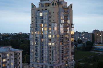 Fototapeta premium Large high-rise building, apartment building in the evening light, lights in the Windows;