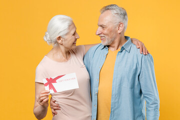 Smiling elderly gray-haired couple woman man in casual clothes isolated on yellow background studio...