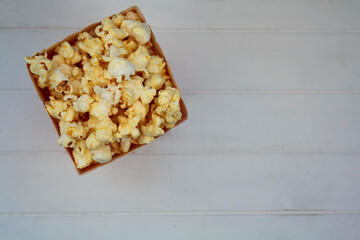 Top view of popcorn box on white wooden table with copy space