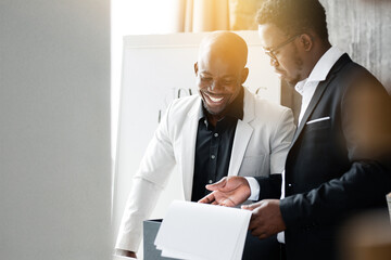 The black attorney shows documents to the Director in a white jacket while in the evening in the...