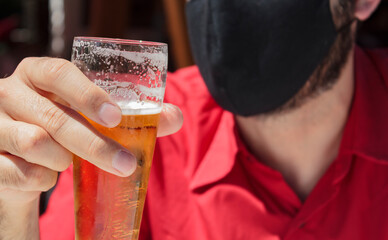 Men with protective face mask holding a glass of beer