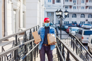 delivery, mail and people concept - man in a protective mask delivering coffee and food in disposable paper bag to customer home