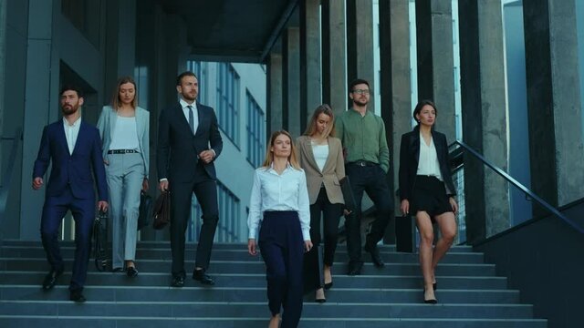 Professional company staff walking downstairs at office building. Successful and ambitious young team of co-workers and female boss. Cooperation. Career.