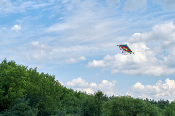 Rainbow kite on a background of summer sky. A variety of white clouds.