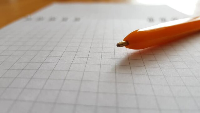 Macro view of a ballpoint pen. New open spiral notebook. Paper in a cell. Side view