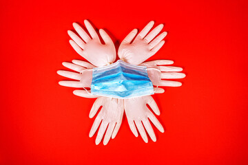 The composition of three pairs of white medical gloves and one blue medical mask on the red background. second lockdown