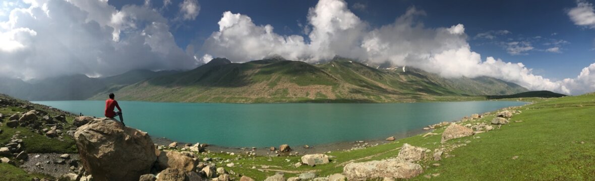 Mountain landscape, lake and mountain range, large panorama. Boy standing on boulder.