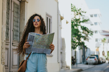 Young hipster woman on summer holidays holding map in city