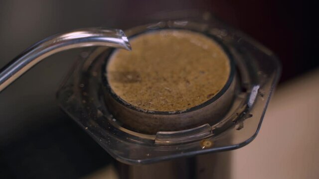 Aeropress coffee alternative making by barista in the cafe. Scandinavian coffee brewing method. Barista pours water to aeropress with coffee using kattle. Advert for cafe, restaurants.
