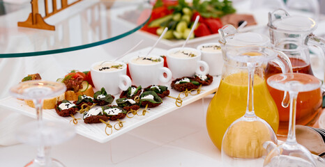 Catering. Dried meat canape, cups of sauce and sandwiches. with juice and glasses.