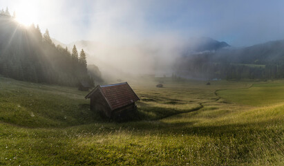 Panorama of foggy morning in the mountains - meadow and hut near Lake Gerold
