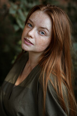 Naklejka premium girl with red hair and freckles on a green background