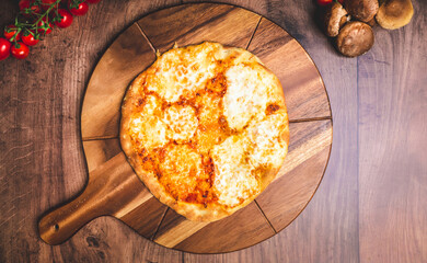 Homemade freshly baked Pizza Margherita with melted mozzarella on the top on a wooden board with lots of decorative vegetables. Concept of fresh hot pizza with free space for your text/decorations.