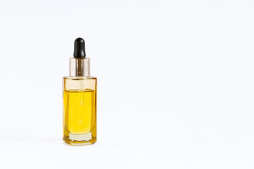 Glass bottle with a pipette with macadamia nut oil on a white background.