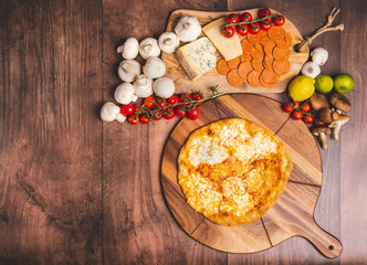 Homemade freshly baked Pizza Margherita with melted mozzarella on the top on a wooden board with lots of decorative vegetables. Concept of fresh hot pizza with free space for your text/decorations.