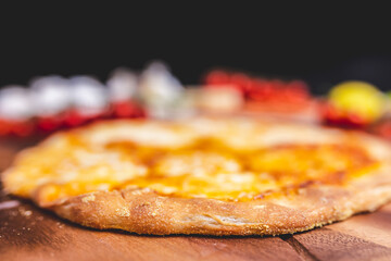 Homemade freshly baked Pizza Margherita with melted mozzarella on the top on a wooden board with lots of decorative vegetables. Concept of fresh hot pizza with free space for your text/decorations.