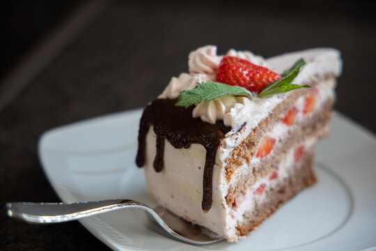 Ein St&uuml;ck Erdbeertorte mit Minze auf einer Kuchengabel
