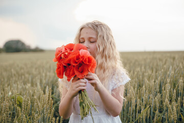beautiful little girl with blond hair in a white dress in the background of a beautiful field. Girl...