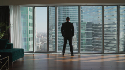 Fototapeta na wymiar man looking on city through the window. Successful businessman in a business office.