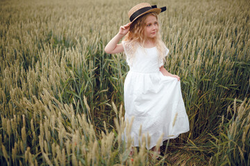 little girl with a straw hat. beautiful little girl with blond hair in a white dress in the background of a beautiful field. Girl with a bouquet of red poppies