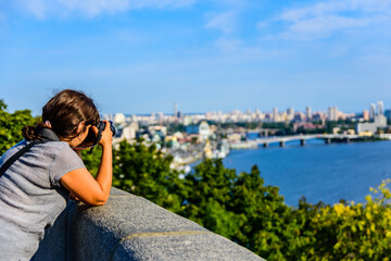 Fototapeta premium Young woman taking a photo of Kiev cityscape and river Dnieper