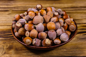 Plate with pile of hazelnuts on a wooden table