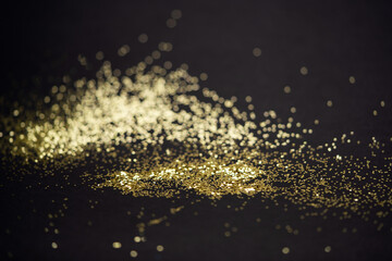 Beautiful Christmas light background. Abstract glitter bokeh and scattered sparkles in gold, on black