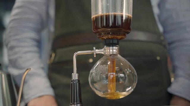 Coffee Syphon alternative method of making in coffee shop and cafe. Scandinavian coffee brewing method. Brewing process in syphon. Coffee pours down to special glass teapot
