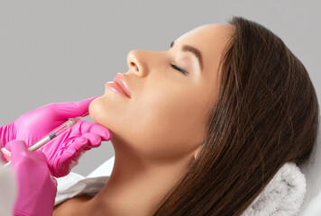 Cosmetologist does injections for lips augmentation and anti wrinkle of a beautiful woman. Her face...