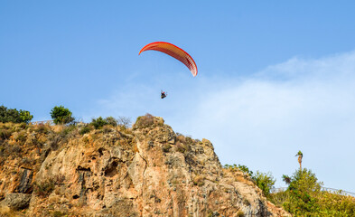 Paraglider flying over the rock in the Antalya, Turkey.  Active lifestyle, extreme sport. Summer...