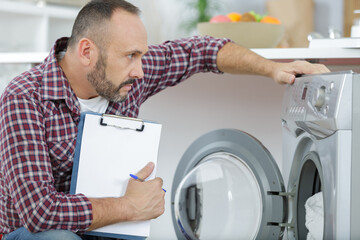 man with clipboard near washing machine