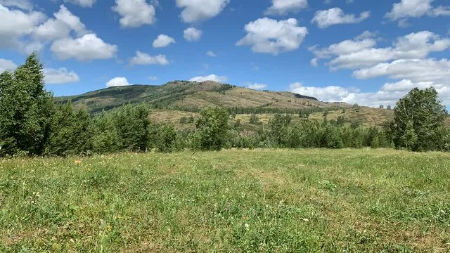 Timelapse. Panoramic view. Beautiful summer landscape. Mountains, blue sky and green fields, forestA group of clouds in the sky